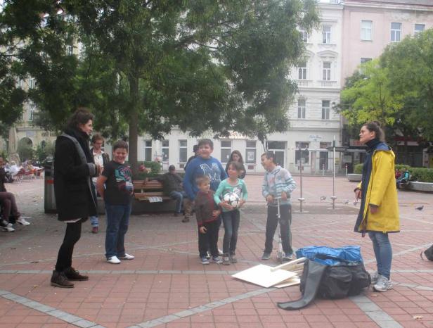 Eine Gruppe von Kindern und Erwachsenen steht auf einem Platz in der Stadt.