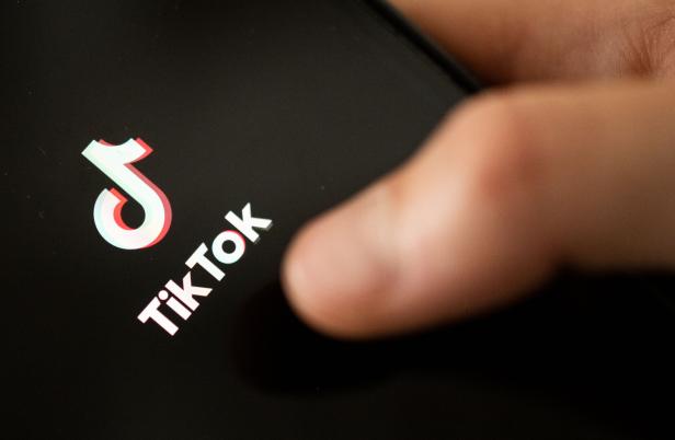 Ein Daumen drückt auf dem Touchscreen auf Tiktok.