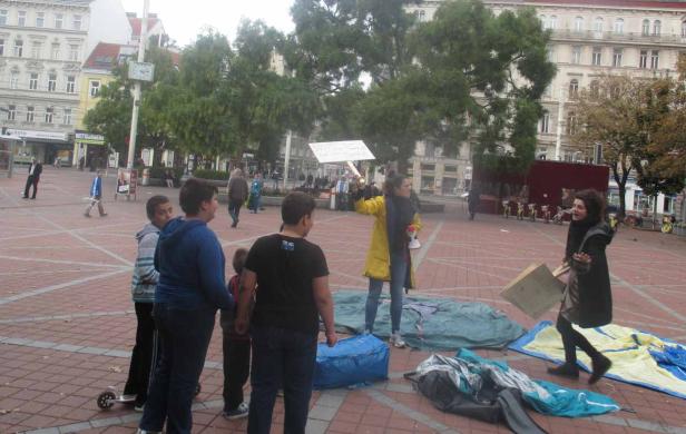 Eine Frau demonstriert mit einem Schild auf einem belebten Platz.