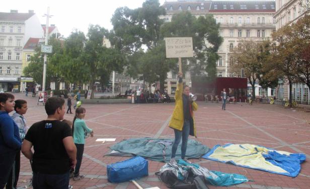Eine Frau hält ein Schild mit der Aufschrift „Mit Zelten den Rechtsruck stoppen“ und spricht in ein Megaphon.
