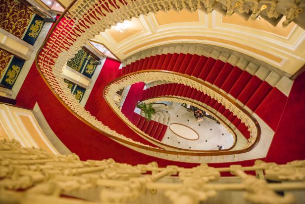 Ein Blick von oben auf ein elegantes Treppenhaus mit rotem Teppich.