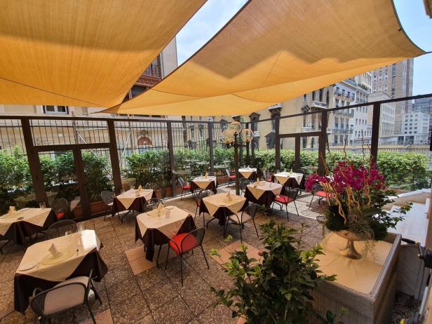 Einladender Restaurantbereich im Freien mit Tischen und Stühlen unter einer Markise.