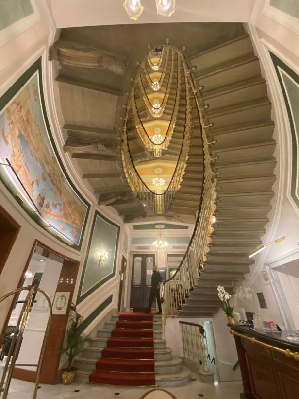 Blick auf ein elegantes Treppenhaus mit rotem Teppich und Wendeltreppe.