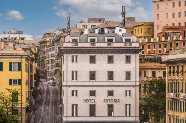 Das Hotel Astoria in Genua, umgeben von farbenfrohen Gebäuden und einer belebten Straße.