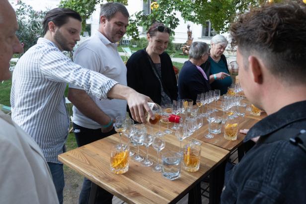 Eine Gruppe von Menschen steht an einem Tisch und probiert Whiskey.