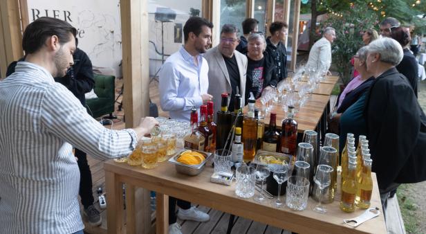 Ein Barkeeper mixt Getränke für eine Gruppe von Menschen an einer Bar.