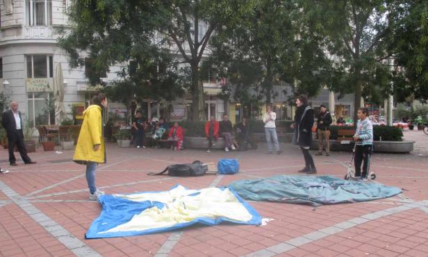 Auf einem Platz bauen Menschen Zelte auf.