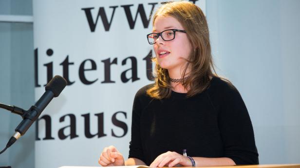 Eine junge Frau mit Brille spricht vor einem Mikrofon im Literaturhaus.