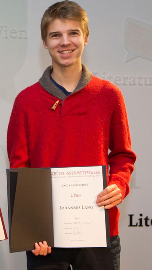 Johannes Lang hält seine Urkunde für den 2. Preis beim Schüler/innen-Wettbewerb in den Händen.