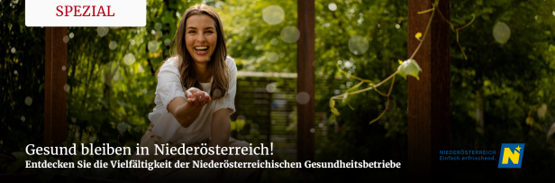 Eine lächelnde Frau streckt ihre Hand in einem Garten aus.