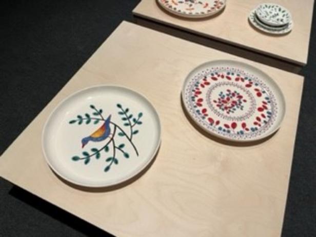 Mehrere dekorative Teller mit Vogel- und Blumenmotiven auf hellen Holzflächen.