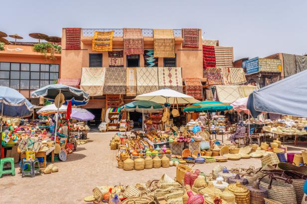 Ein belebter Marktplatz mit Körben, Hüten und Teppichen in Marrakesch, Marokko.