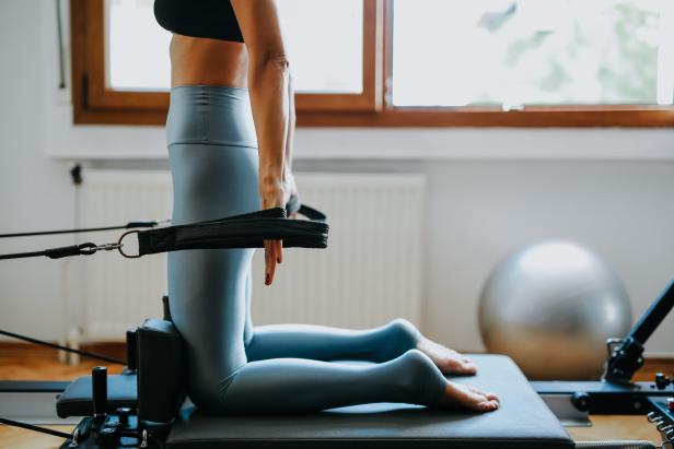 Eine Frau macht Pilatesübungen auf einem Reformer.