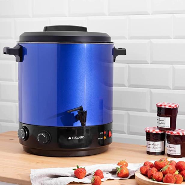 Ein blauer Einkochautomat der Marke Navaris steht neben Erdbeeren und Marmeladengläsern.