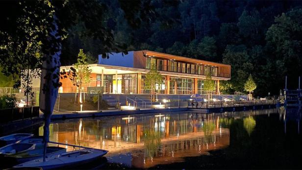 Das Waldcafé Thalersee spiegelt sich nachts im Wasser.