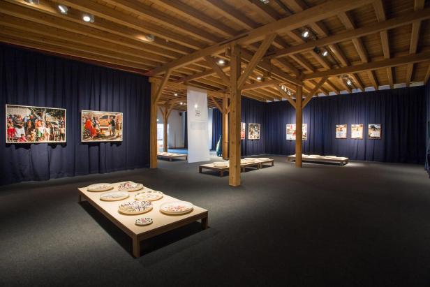 Innenansicht einer Kunstausstellung mit Fotografien und bemalten Tellern.