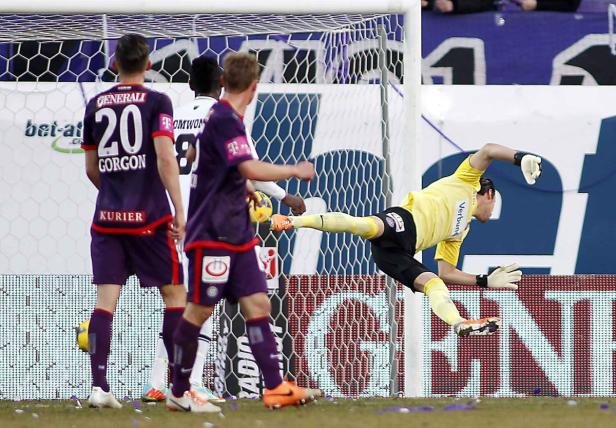 Ein Torwart springt, um einen Fußball zu halten, während andere Spieler zusehen.