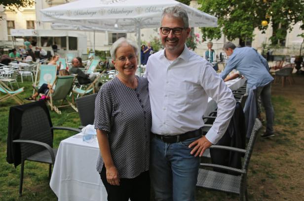 Zwei Personen posieren lächelnd im Freien vor einem Restaurant.