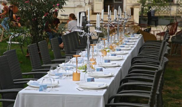 Ein langer, weiß gedeckter Tisch mit Stühlen im Freien für eine Feierlichkeit.