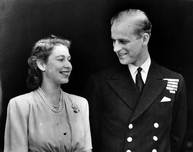 Ein Schwarzweißfoto von Königin Elizabeth II. und Prinz Philip, die sich anlächeln.