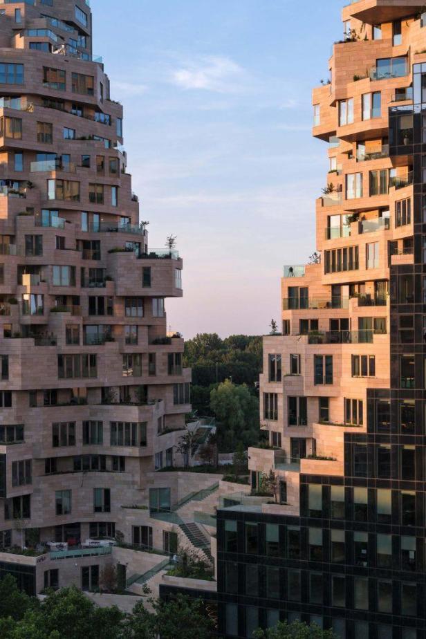 Zwei moderne Wohngebäude mit terrassenförmigen Balkonen im Abendlicht.