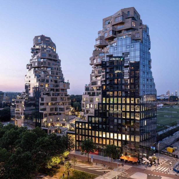 Zwei moderne Hochhäuser mit ungewöhnlicher Architektur ragen in den Abendhimmel.