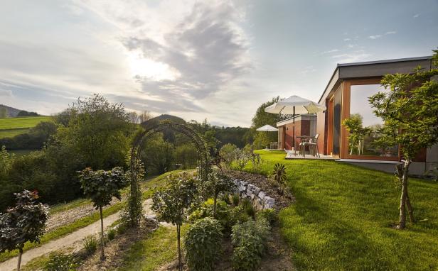 Ein Garten mit einem Weg, der zu modernen Gebäuden mit Terrassen führt.