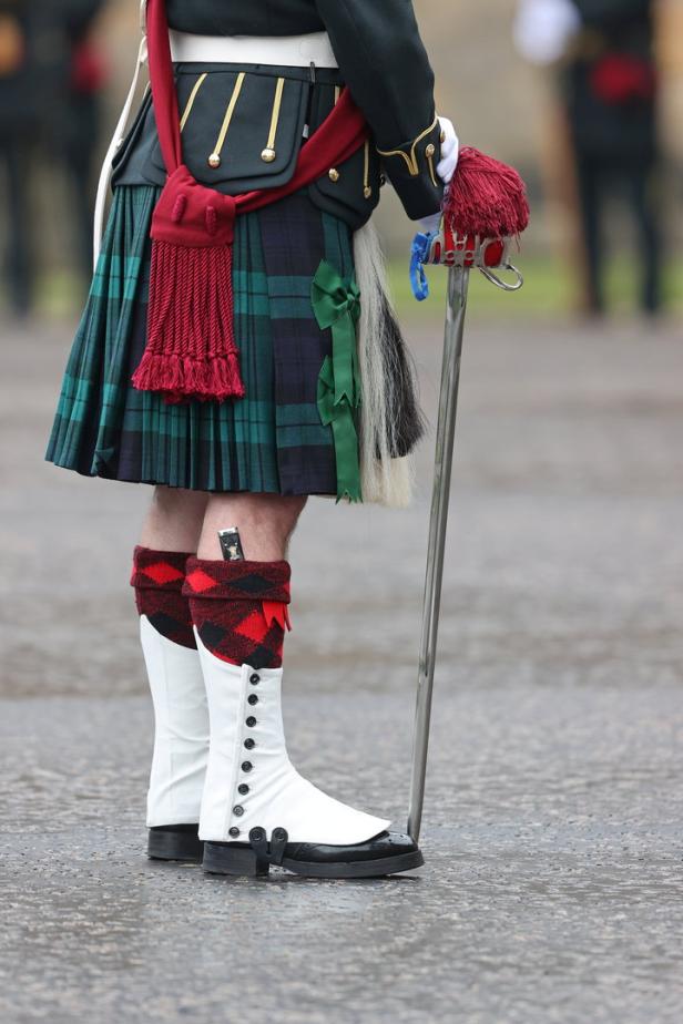 Ein Mann im traditionellen schottischen Kilt mit Schwert und weißen Stiefeln.