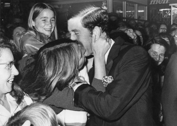 Prinz Charles küsst eine junge Frau in einer Menschenmenge.