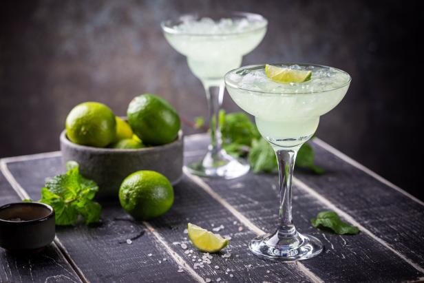 Ein Margarita-Cocktail mit Limette und Eiswürfeln auf einem Holztisch.