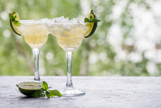 Zwei Margaritas mit Limetten und Minze auf einem Tisch.