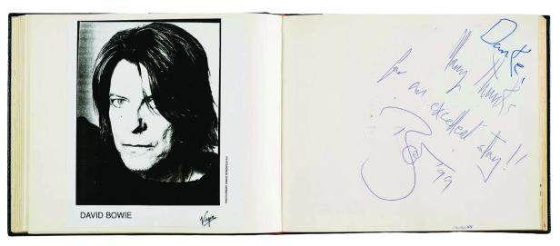 Ein geöffnetes Buch zeigt ein Schwarz-Weiß-Porträt von David Bowie und eine handsignierte Seite.
