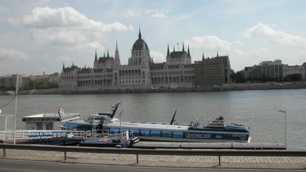 Ein Ausflugsschiff liegt vor dem ungarischen Parlament in Budapest.