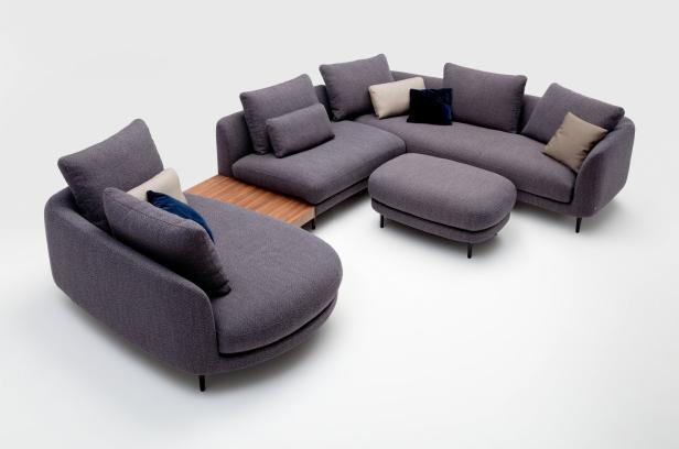 Ein graues modulares Sofa mit Kissen und einem Holztisch auf einem weißen Hintergrund.