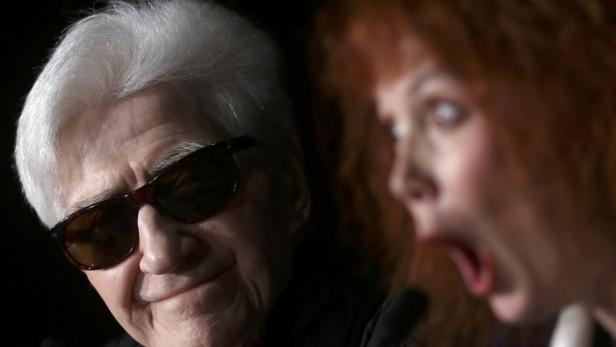 Ein Mann mit Sonnenbrille und weißem Haar, neben einer Frau mit offenem Mund.