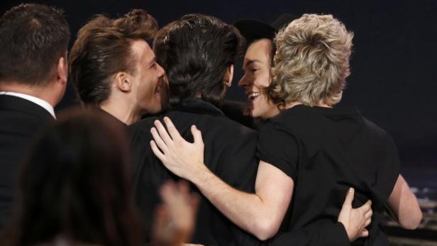 Die Mitglieder der Band One Direction umarmen sich auf der Bühne.