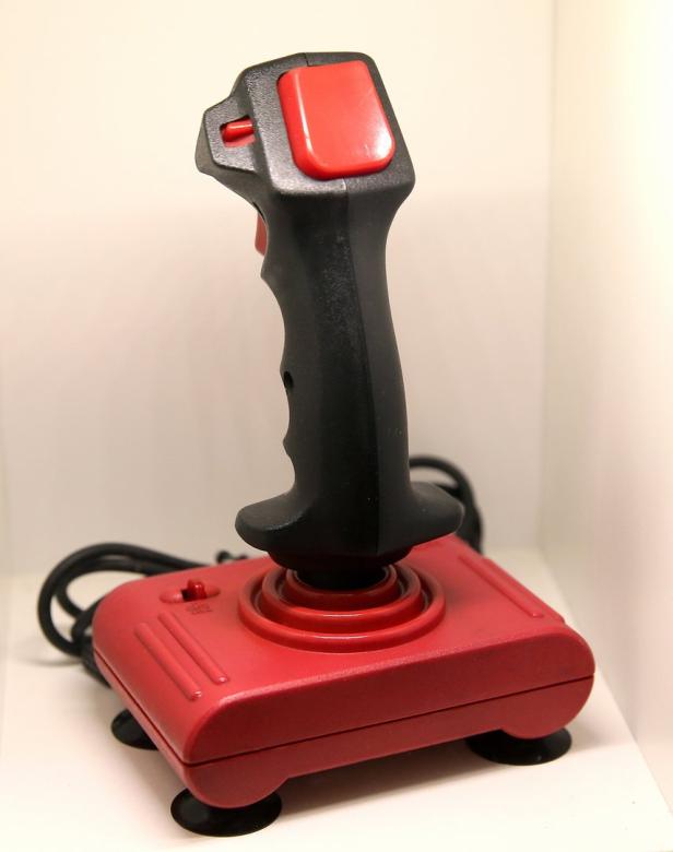 Ein roter und schwarzer Joystick mit einem roten Knopf oben drauf.