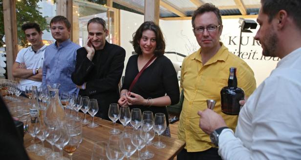 Eine Gruppe von Menschen steht an einem Tisch mit Gläsern und einer Flasche Corona.