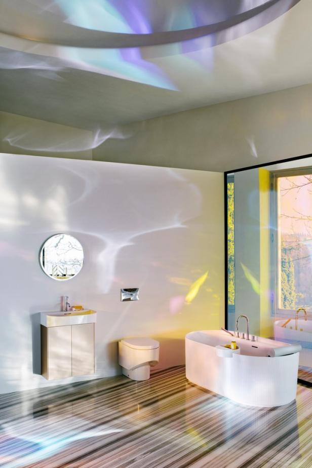 Ein Badezimmer mit Badewanne, Toilette und Waschbecken, beleuchtet durch farbiges Licht.