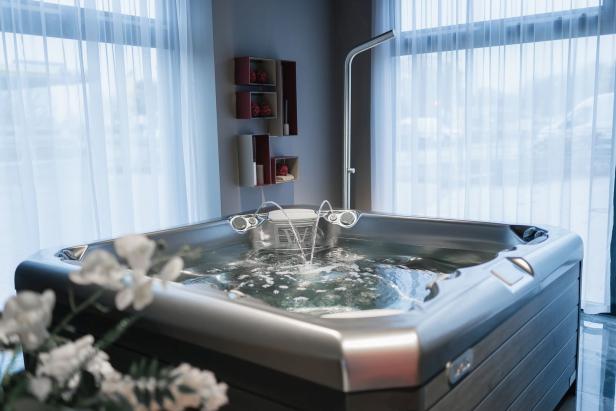 Ein sprudelnder Whirlpool steht vor einem Fenster mit weißen Vorhängen.