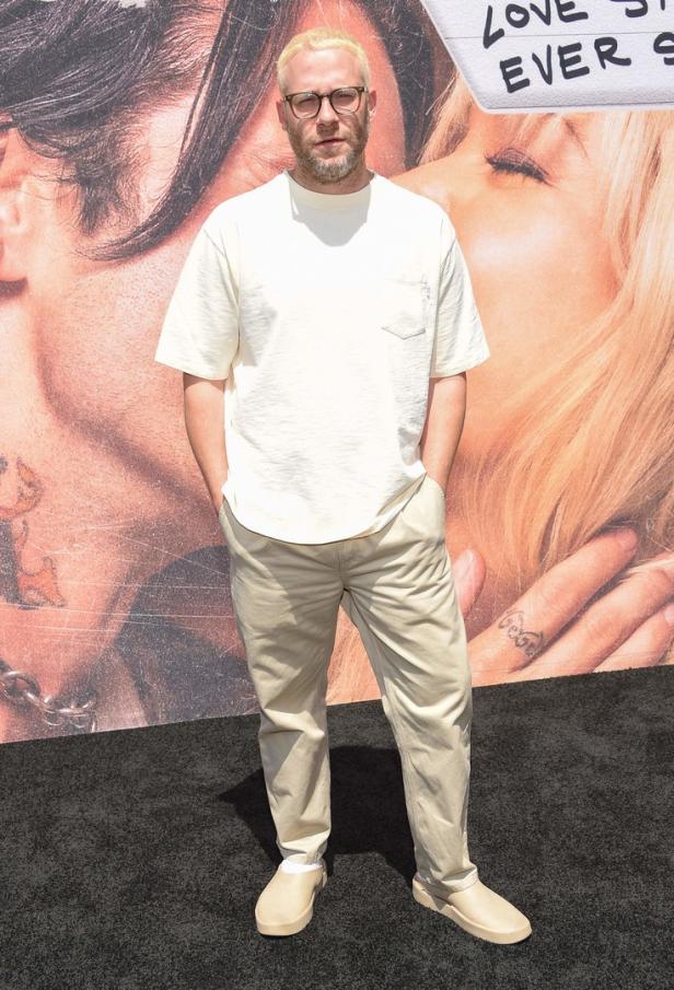 Seth Rogen posiert vor einem Poster für den Film „Pam & Tommy“.