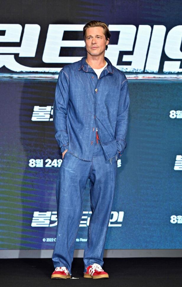 Brad Pitt posiert in einem blauen Anzug vor einer Filmkulisse.