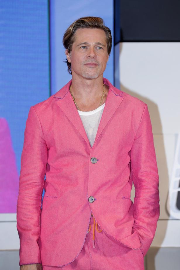 Brad Pitt trägt einen pinkfarbenen Anzug und eine goldene Halskette.