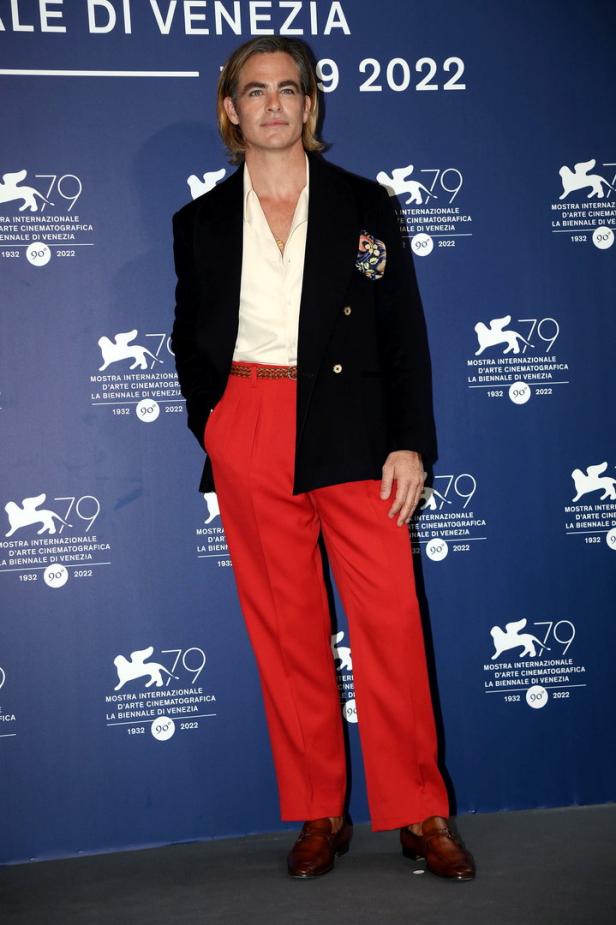 Chris Pine posiert in einem schwarzen Sakko und einer roten Hose auf dem Filmfestival von Venedig 2022.