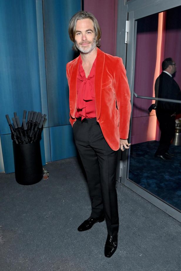 Chris Pine trägt ein rotes Samtsakko und eine rote Bluse.
