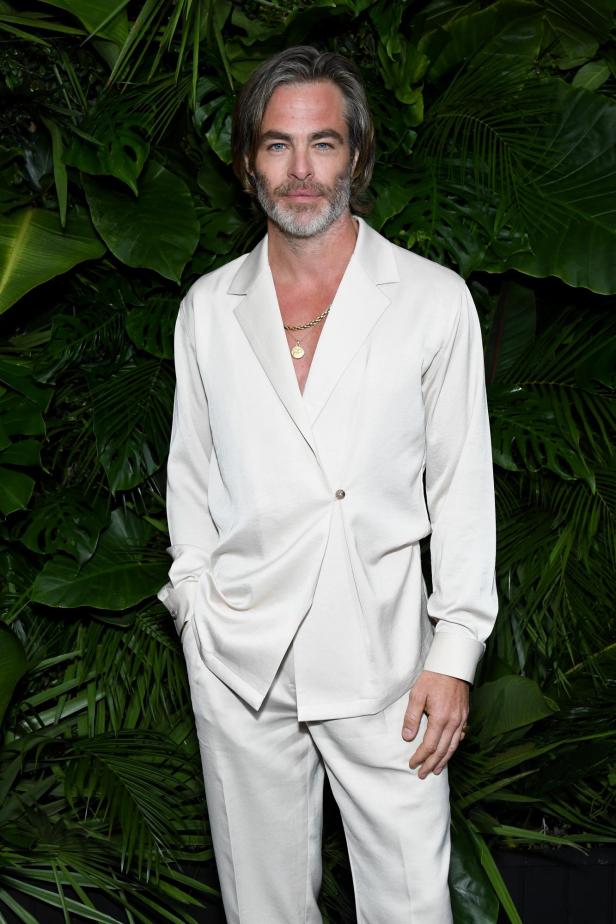 Chris Pine posiert vor einem Hintergrund aus tropischen Pflanzen.