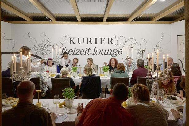 Gäste sitzen an einer festlichen Tafel in der „Kurier freizeit.lounge“ bei Kerzenschein.