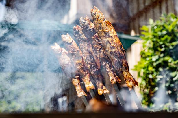 Geräucherter Fisch wird auf Spießen gegrillt.