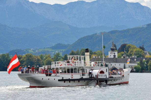 Das Raddampfschiff „Gisela“ fährt auf einem See vor einer Bergkulisse.