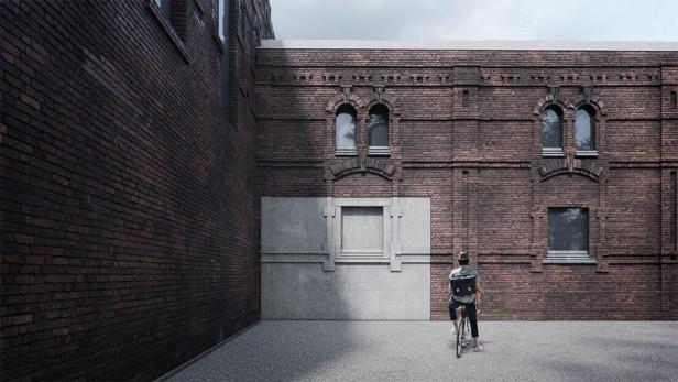 Ein Mann fährt mit dem Fahrrad vor einer roten Backsteinmauer.